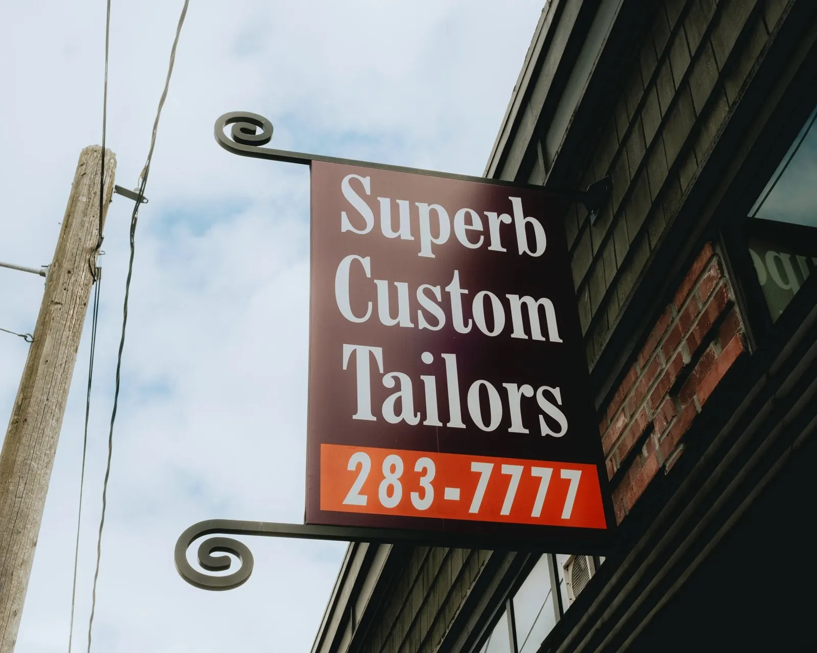 The Superb Custom Tailors hanging sign above the shop on W Galer St